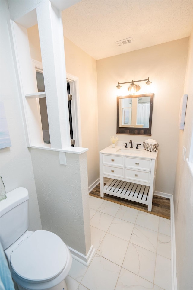 bathroom with vanity, a textured ceiling, and toilet