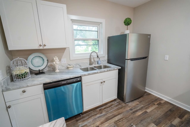 kitchen featuring appliances with stainless steel finishes, light stone counters, sink, dark hardwood / wood-style floors, and white cabinetry