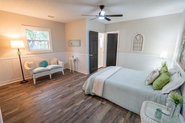 bedroom with ceiling fan, dark hardwood / wood-style flooring, and a textured ceiling