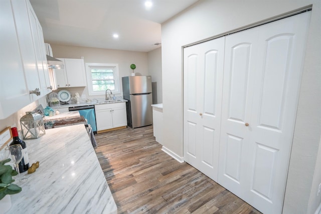 kitchen with hardwood / wood-style floors, white cabinets, stainless steel appliances, and sink