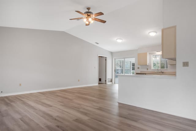 unfurnished living room with vaulted ceiling, sink, ceiling fan, and light hardwood / wood-style flooring