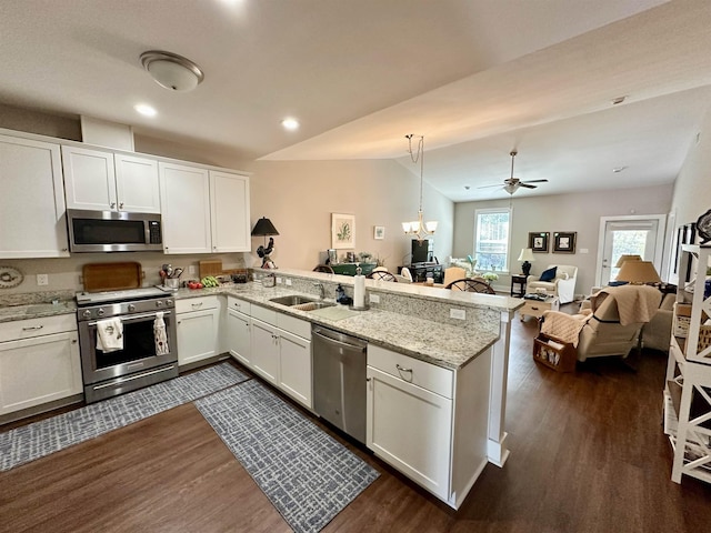 kitchen featuring dark wood-type flooring, kitchen peninsula, pendant lighting, stainless steel appliances, and white cabinets