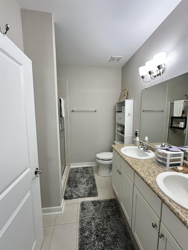 bathroom with toilet, vanity, a shower with door, and tile patterned flooring