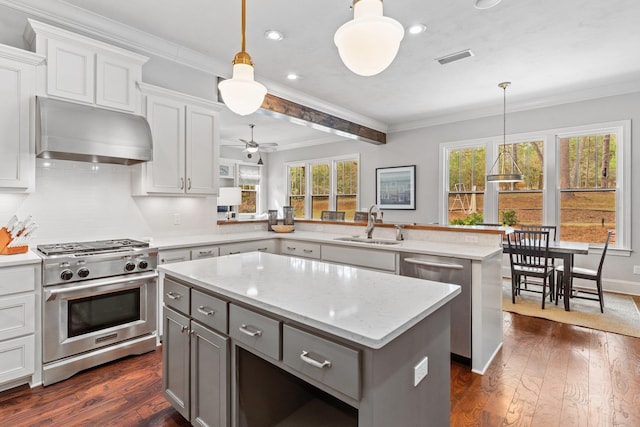 kitchen featuring decorative light fixtures, range hood, kitchen peninsula, and appliances with stainless steel finishes