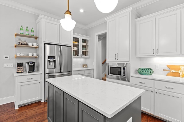 kitchen with decorative light fixtures, ornamental molding, stainless steel appliances, light stone countertops, and white cabinets