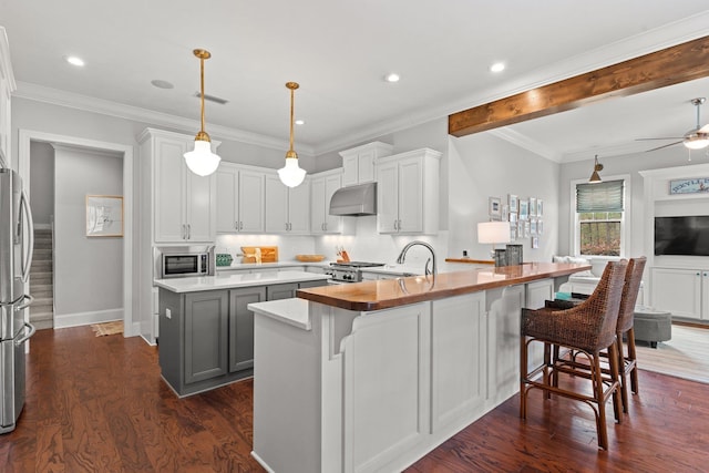 kitchen with stainless steel microwave, an island with sink, white cabinets, dark hardwood / wood-style flooring, and hanging light fixtures