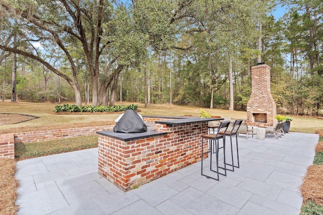 view of patio / terrace with an outdoor brick fireplace and a bar