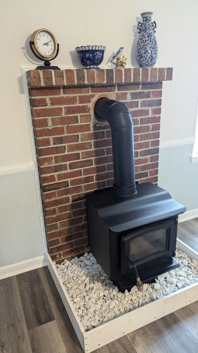 interior details with a wood stove, a decorative wall, wood finished floors, and a wainscoted wall