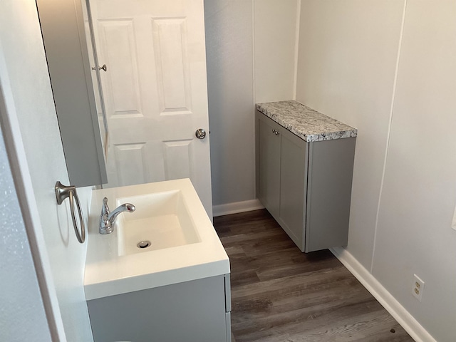 bathroom with baseboards, wood finished floors, and vanity