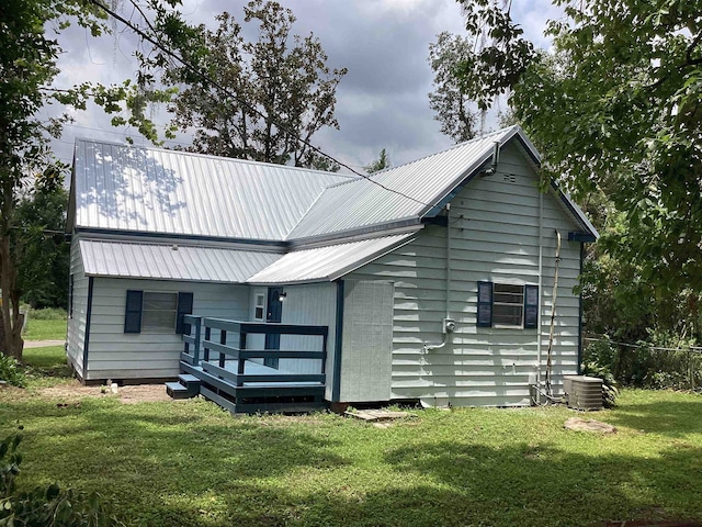 rear view of house featuring a yard, central air condition unit, metal roof, and a wooden deck