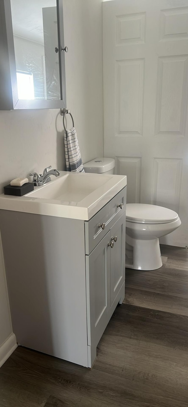 half bath featuring toilet, wood finished floors, and vanity