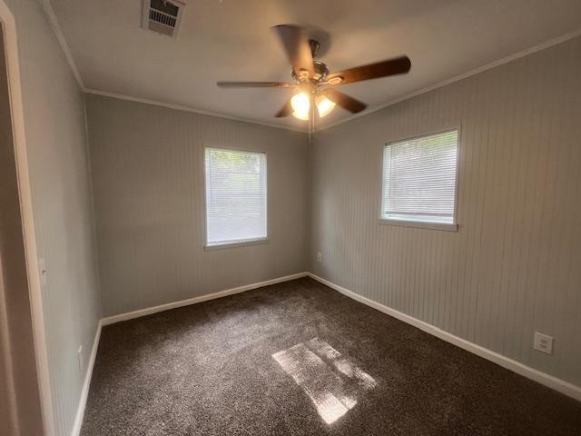 carpeted empty room featuring crown molding, baseboards, visible vents, and ceiling fan