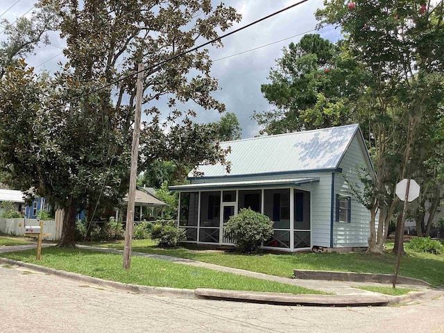 view of front of house featuring a front lawn, a sunroom, and metal roof