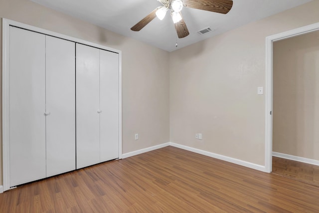 unfurnished bedroom with ceiling fan, a closet, and hardwood / wood-style flooring