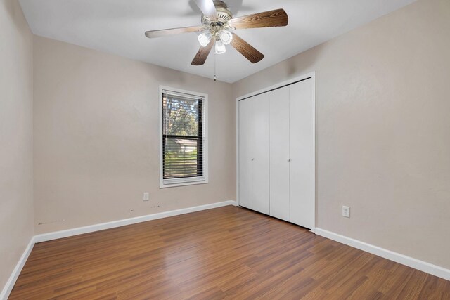 unfurnished bedroom featuring ceiling fan, a closet, and hardwood / wood-style flooring