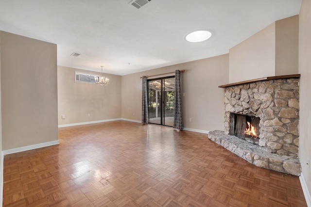 unfurnished living room with a stone fireplace, parquet floors, and a notable chandelier