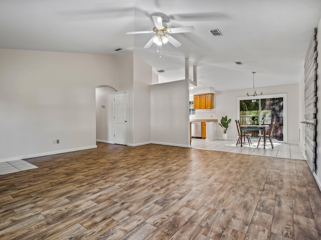 1 Black Foot Rd, Crawfordville, FL 32327 - unfurnished living room with a ceiling fan, light wood-type flooring, vaulted ceiling, arched walkways, and a chandelier