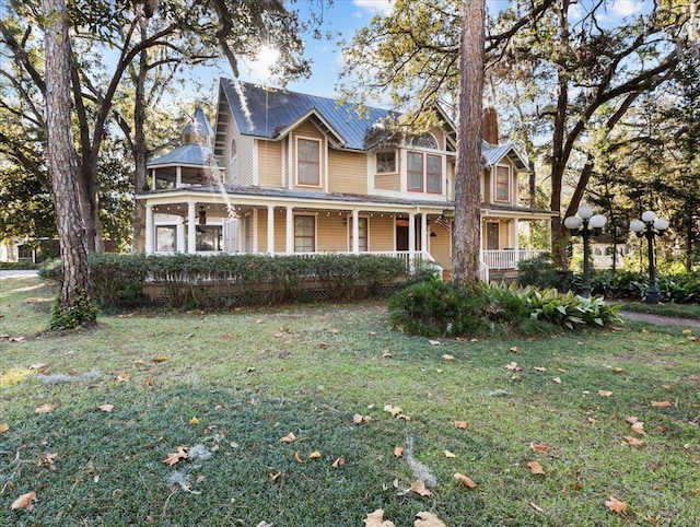 233 NE Maggie Cir, Steinhatchee, FL 32359 - victorian house featuring covered porch, a front lawn, and metal roof