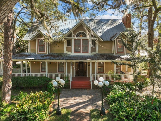 233 NE Maggie Cir, Steinhatchee, FL 32359 - victorian home featuring metal roof, covered porch, a chimney, and a standing seam roof