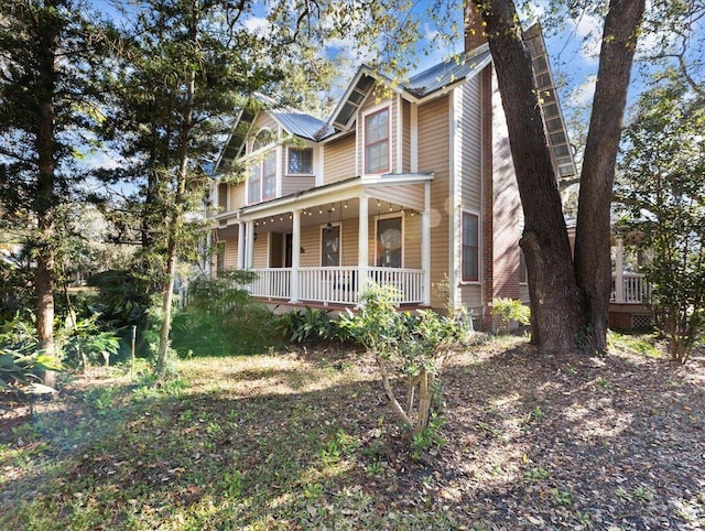233 NE Maggie Cir, Steinhatchee, FL 32359 - victorian home featuring covered porch, metal roof, and a chimney