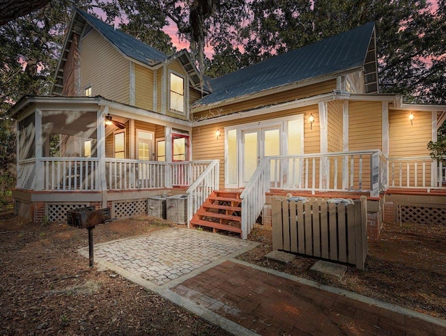 233 NE Maggie Cir, Steinhatchee, FL 32359 - back of property at dusk featuring metal roof, a sunroom, a patio, and a wooden deck