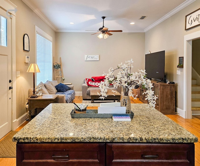 kitchen with crown molding, light hardwood / wood-style flooring, ceiling fan, dark brown cabinets, and light stone counters