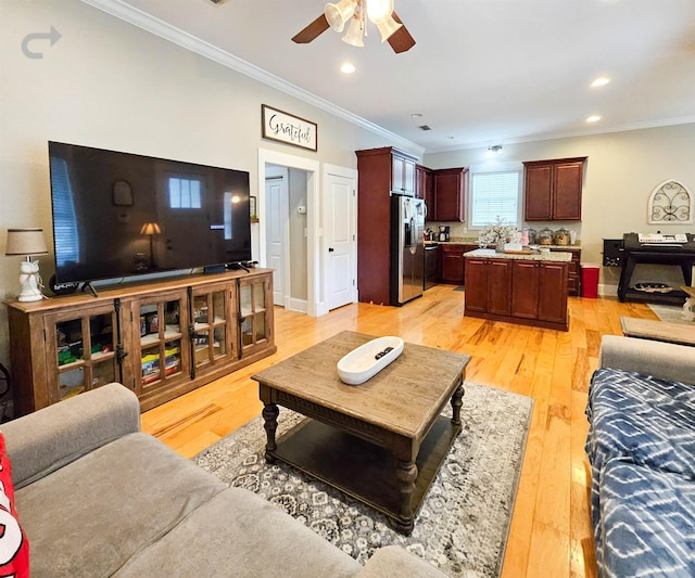 living room featuring ceiling fan, ornamental molding, and light hardwood / wood-style flooring