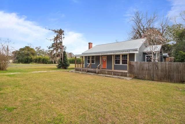 view of front of house with a chimney, a porch, metal roof, fence, and a front lawn