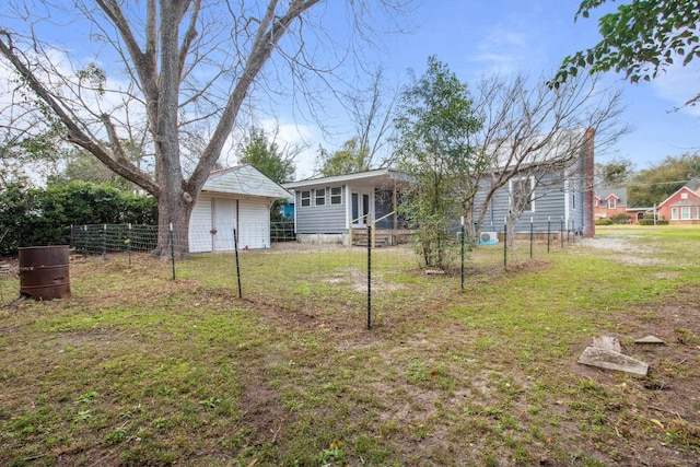 back of property featuring fence, an outdoor structure, and a yard