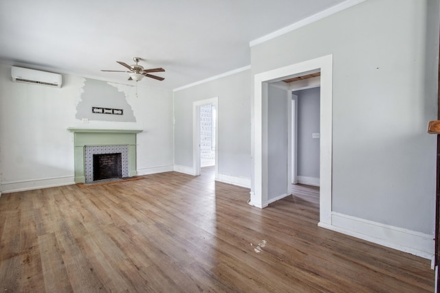 unfurnished living room with a wall unit AC, a fireplace, a ceiling fan, baseboards, and crown molding