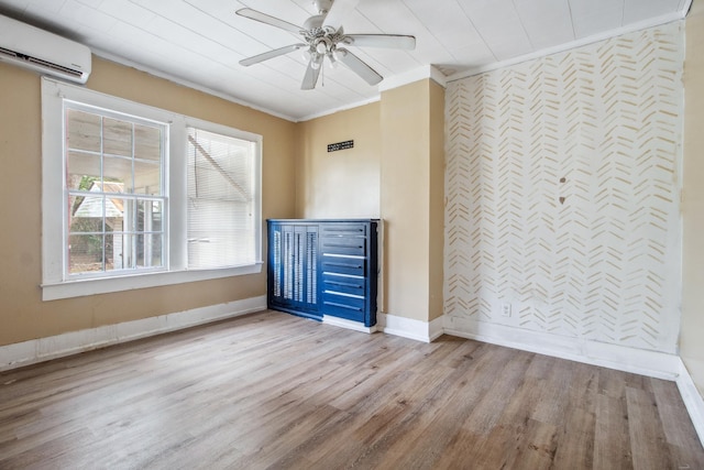 interior space featuring a wall unit AC, crown molding, an accent wall, wood finished floors, and baseboards