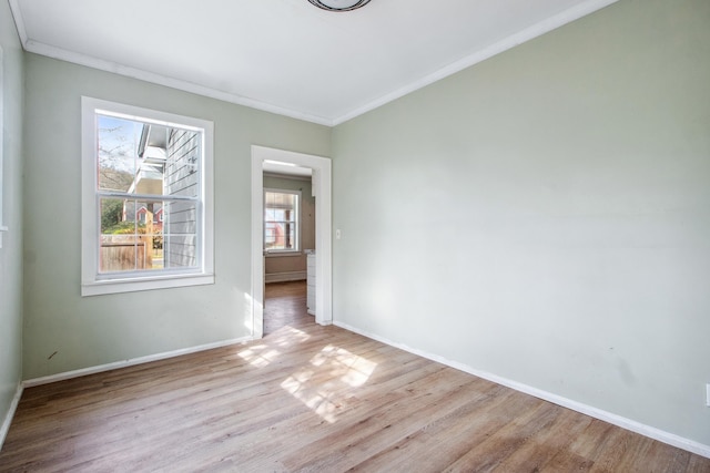 spare room with ornamental molding, wood finished floors, and baseboards