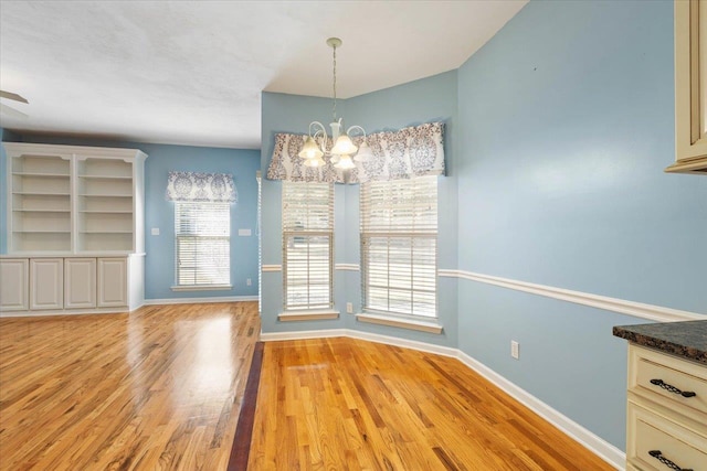 unfurnished dining area featuring light wood-type flooring and a chandelier