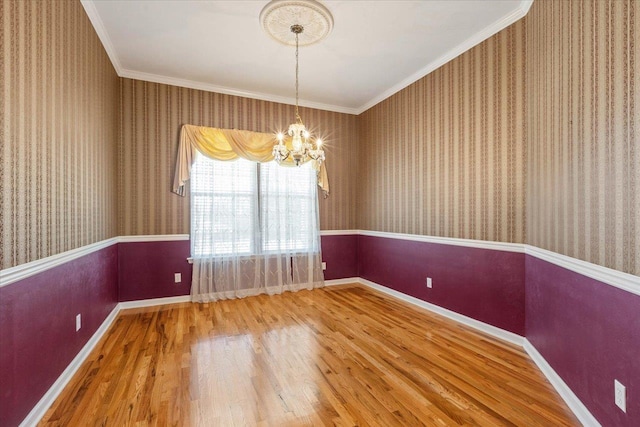 unfurnished room featuring hardwood / wood-style flooring, a notable chandelier, and ornamental molding