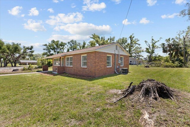 603 W Ash St, Perry, FL 32347 - view of home's exterior featuring brick siding, a lawn, and central AC