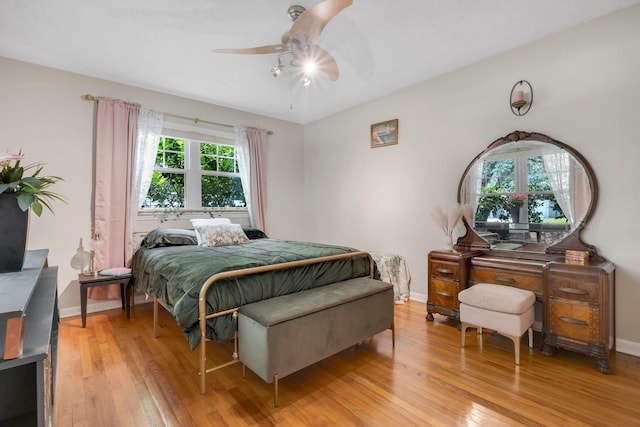 bedroom with light wood finished floors, baseboards, and a ceiling fan