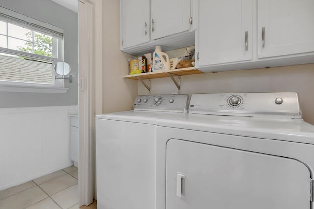 laundry room featuring washing machine and clothes dryer, light tile patterned floors, wainscoting, and cabinet space