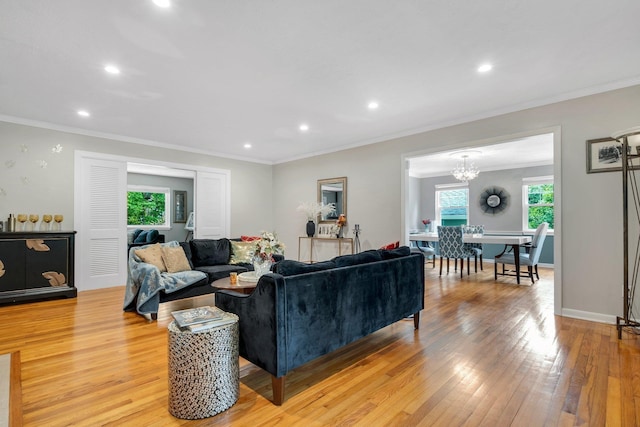 living room with light wood-style floors, ornamental molding, recessed lighting, a chandelier, and baseboards