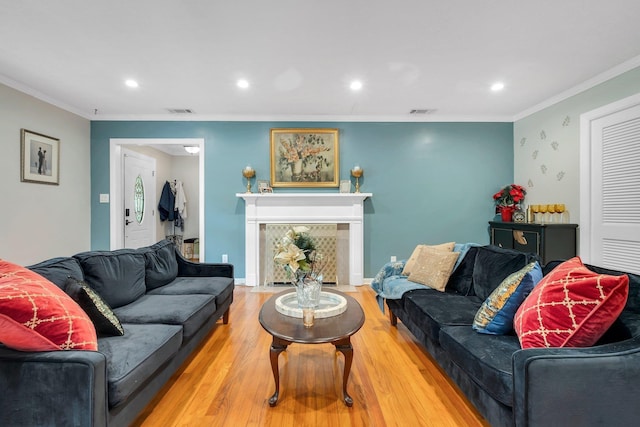 living area with wood finished floors, recessed lighting, crown molding, and a fireplace