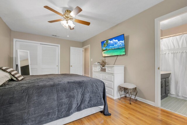 bedroom featuring light wood-style floors, baseboards, a closet, ceiling fan, and ensuite bath