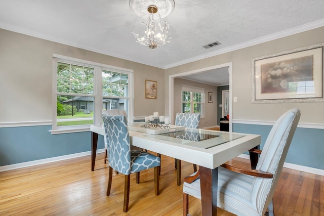 dining room featuring a chandelier, light wood-style flooring, baseboards, and ornamental molding