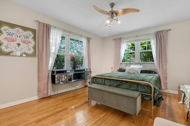 bedroom with multiple windows, light wood-style floors, baseboards, and ceiling fan