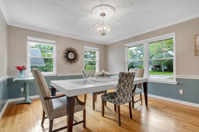 dining area with a chandelier, ornamental molding, light wood-style floors, a textured ceiling, and baseboards