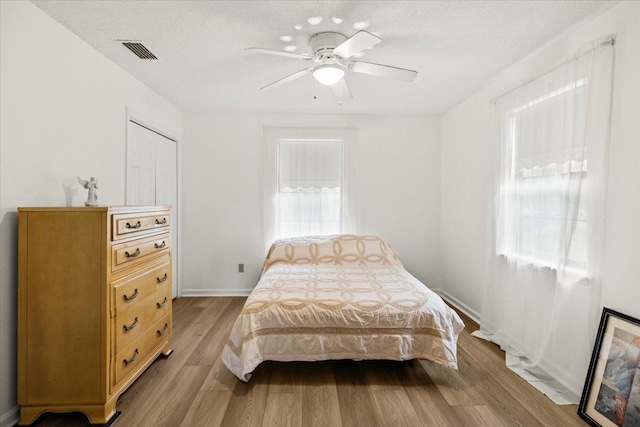 bedroom with a textured ceiling, light hardwood / wood-style flooring, and ceiling fan