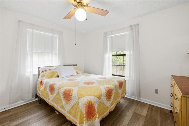 bedroom with ceiling fan, a textured ceiling, and dark hardwood / wood-style flooring