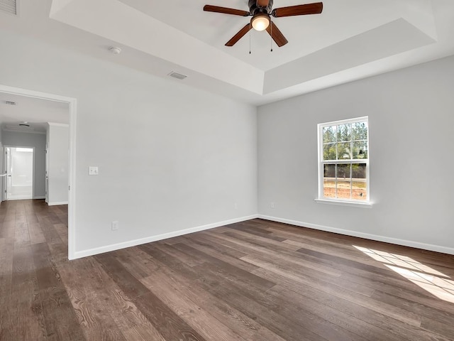 unfurnished room featuring ceiling fan, a raised ceiling, and dark wood-type flooring