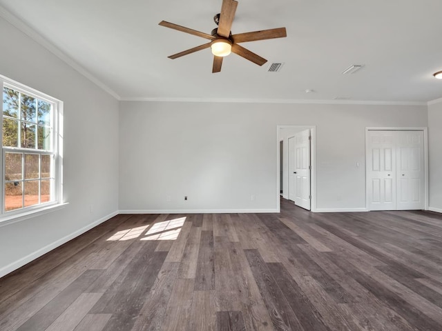 empty room featuring ceiling fan, crown molding, and dark wood-type flooring