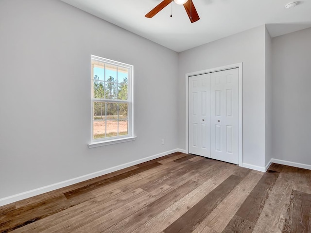 unfurnished bedroom with a closet, hardwood / wood-style flooring, and ceiling fan