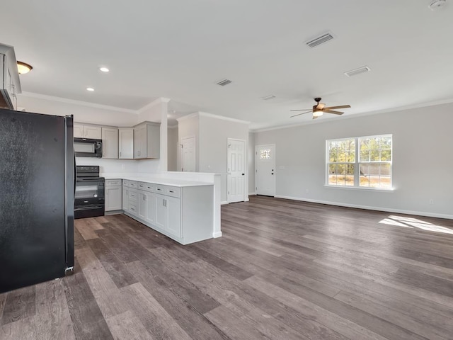 kitchen with gray cabinetry, crown molding, black appliances, and dark hardwood / wood-style floors