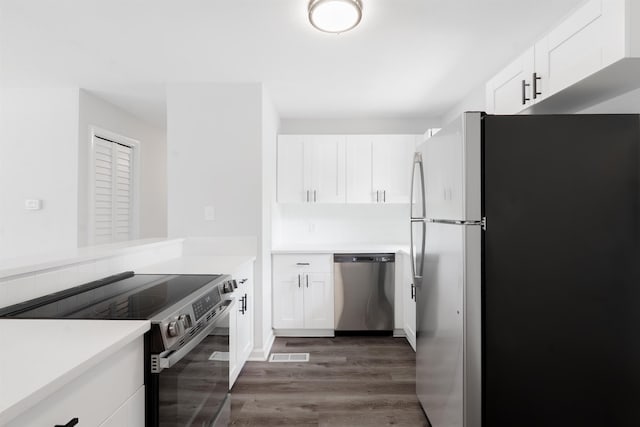 kitchen featuring white cabinets, dark wood finished floors, stainless steel appliances, light countertops, and visible vents